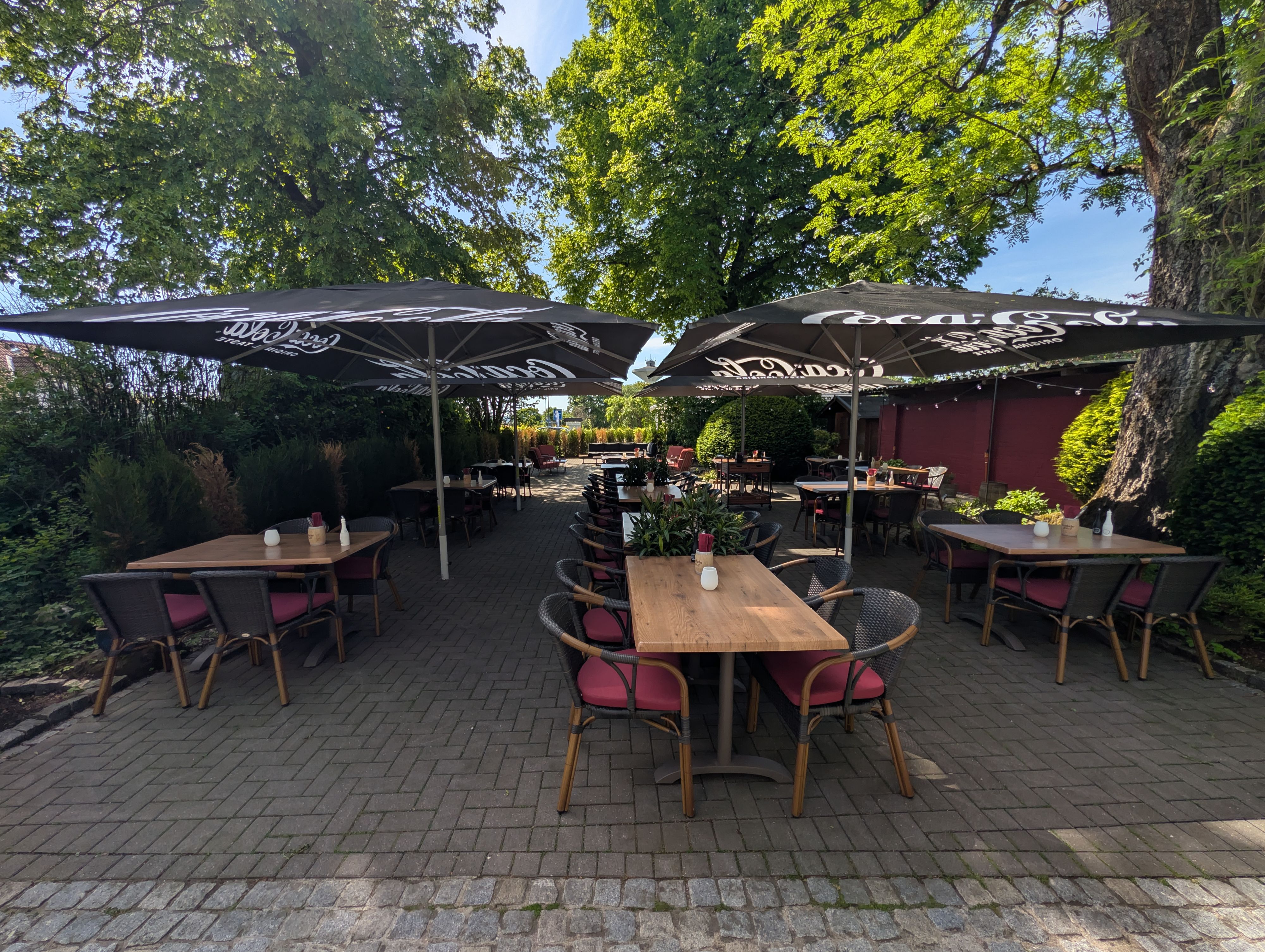 Biergarten mit Sonnenschirmen unter Bäumen